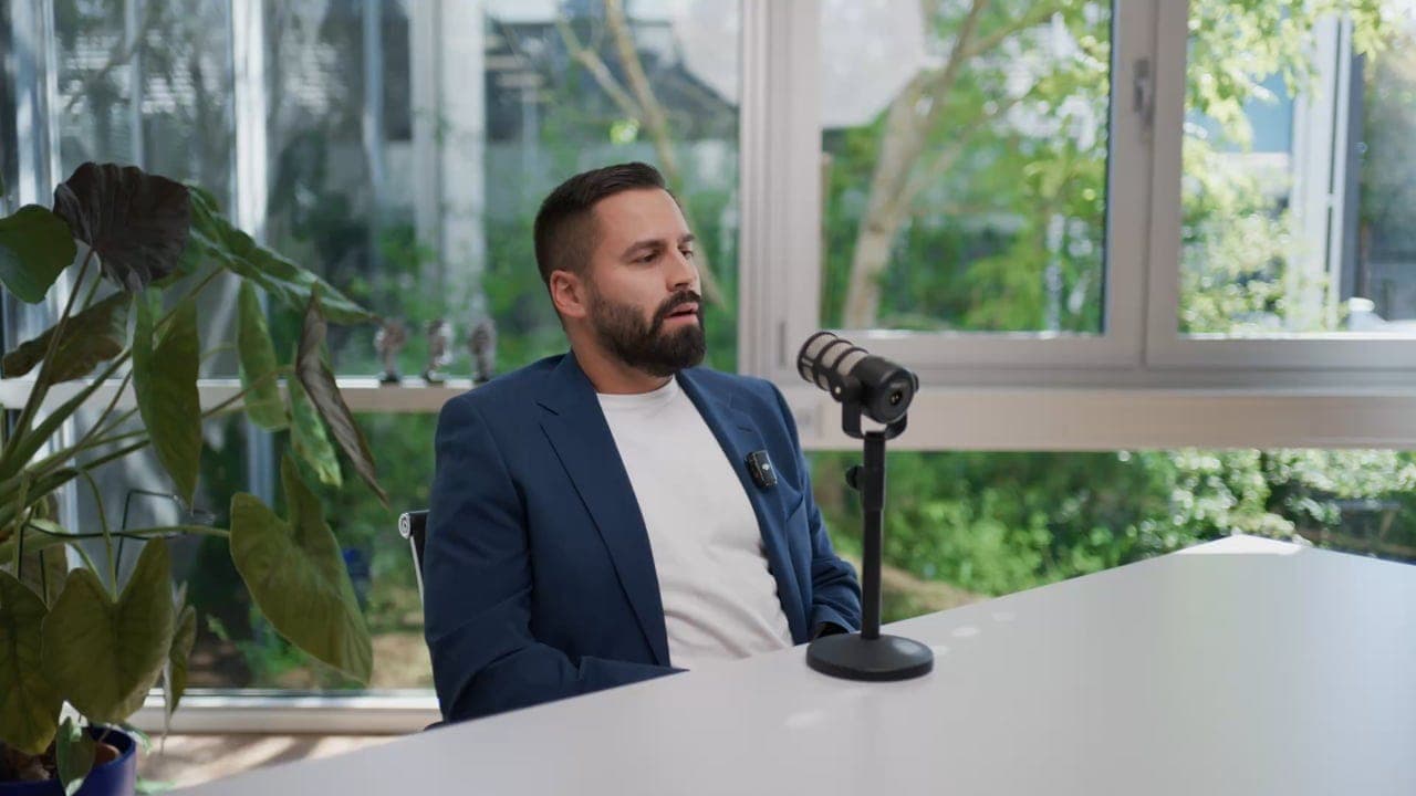 Marlon Marques im Gespräch am Tisch, vor ihm ein Mikrofon